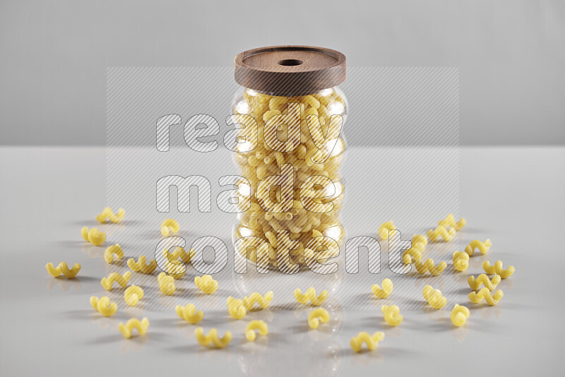 Raw pasta in a glass jar on light grey background