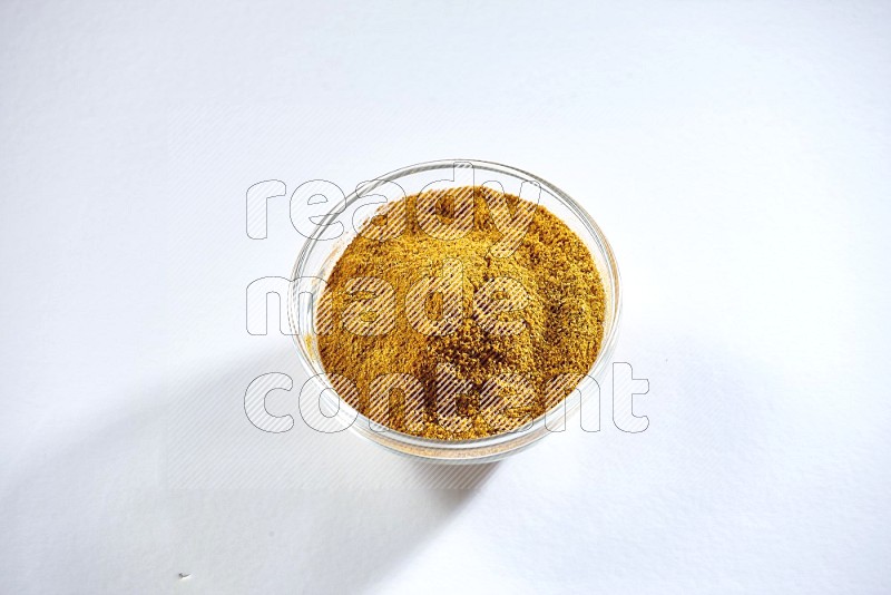 A glass bowl full of turmeric powder on white flooring