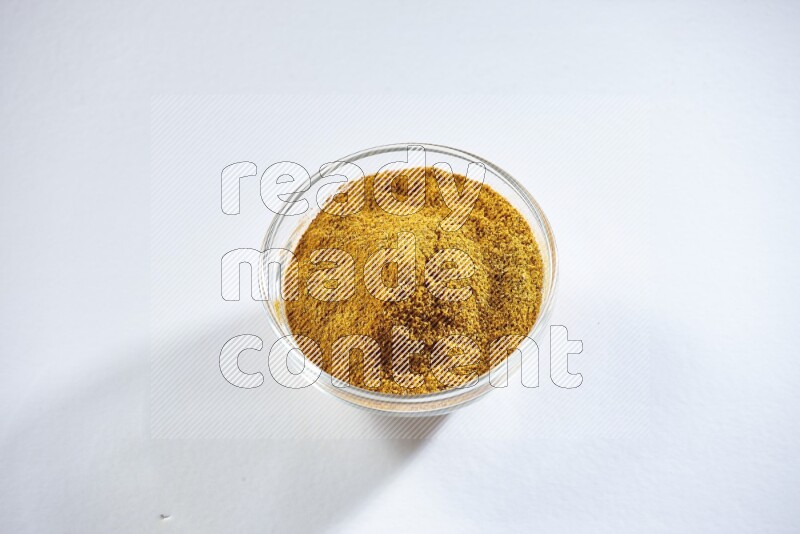 A glass bowl full of turmeric powder on white flooring