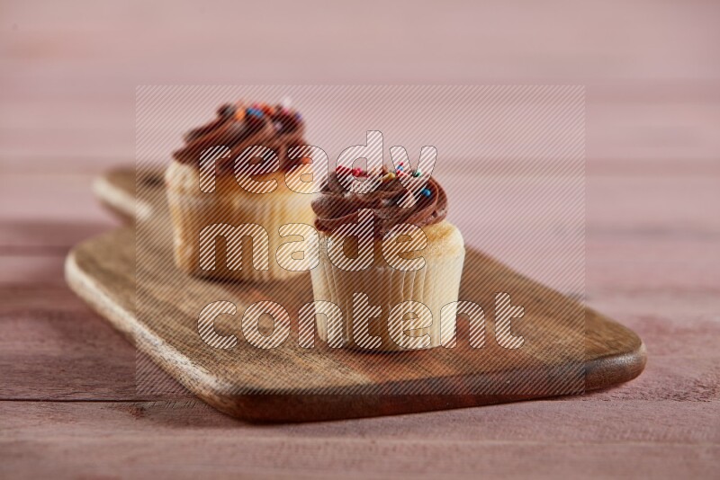 Vanilla mini cupcake topped with chocolate cream on a wooden board