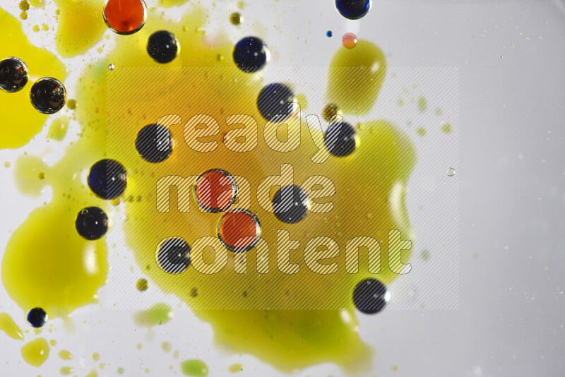 Close-ups of abstract red, blue, yellow and green watercolor drops on oil Surface on white background