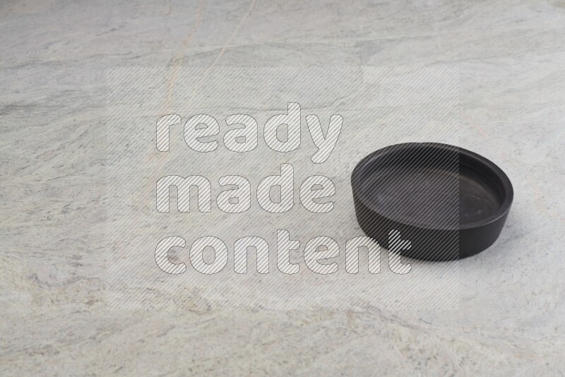 A black pottery oven bowl on grey marble background