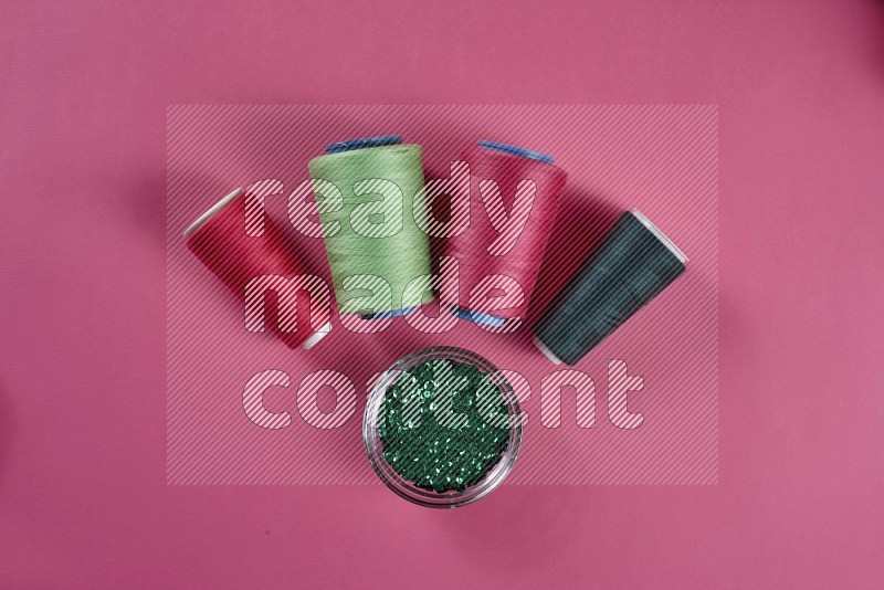 Green sewing supplies on pink background