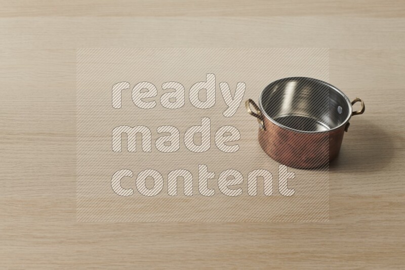 A small copper pot on light wooden background