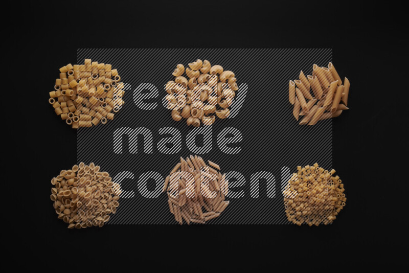 Different pasta types in bunches on black background