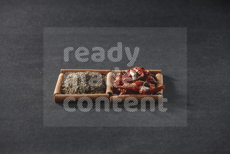 مربعان من أعواد القرفة ممتلئان بالفلفل الحار المجفف وحبوب الكمون علي خلفية سوداء