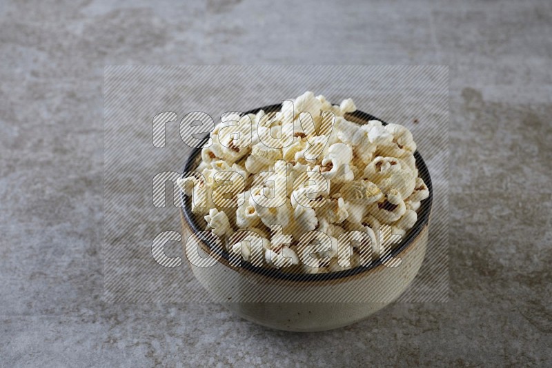 popcorn in multi-colored pottery bowl on a grey textured countertop