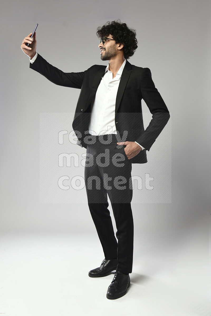 A man wearing formal standing and taking a selfie on white background