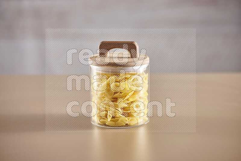 Raw pasta in glass jars on beige background