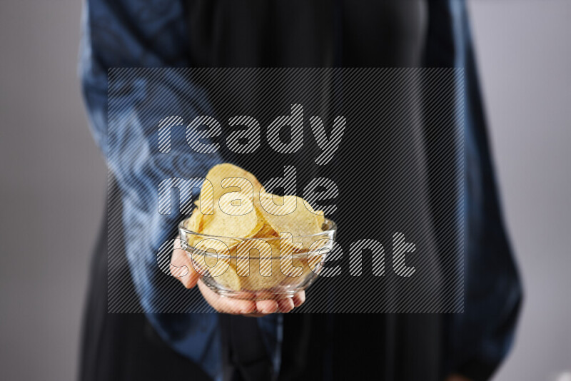 Woman in abaya holding different kinds of snacks in different positions
