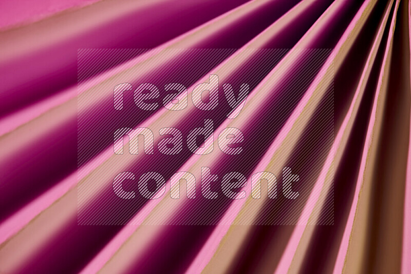 An image presenting an abstract paper pattern of lines in pink and gold tones
