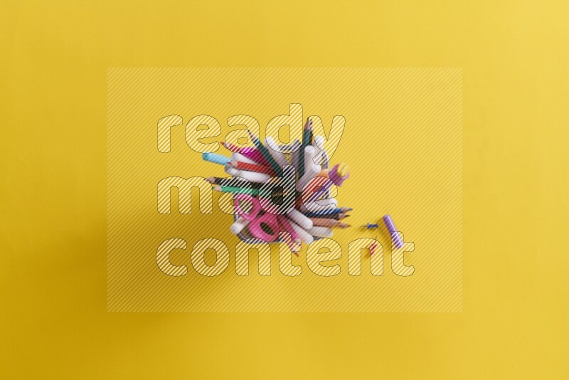 بعض الأقلام والمستلزمات المدرسية في مقلمة معدنية علي خلفية صفراء