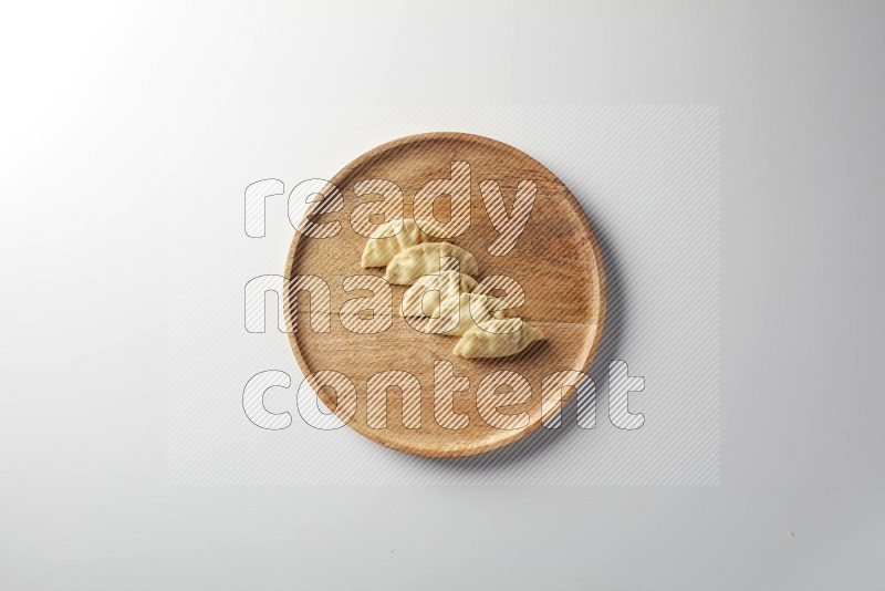 Five Sambosas on a wooden round plate on a white background