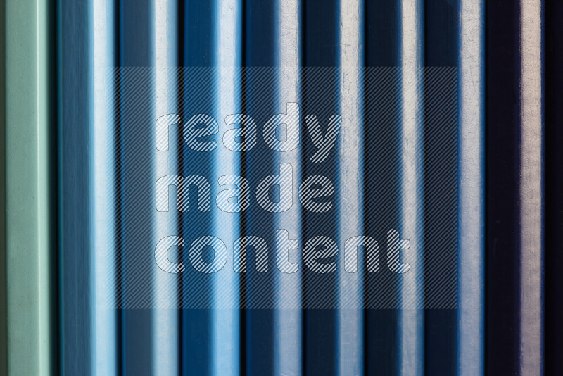 مجموعة من أقلام الرصاص الملونة مرتبة لتعرض تدرجا من الألوان الزرقاء علي خلفية رمادية