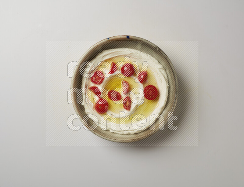Lebnah garnished with cherry tomato in a grey pottery plate on a white background