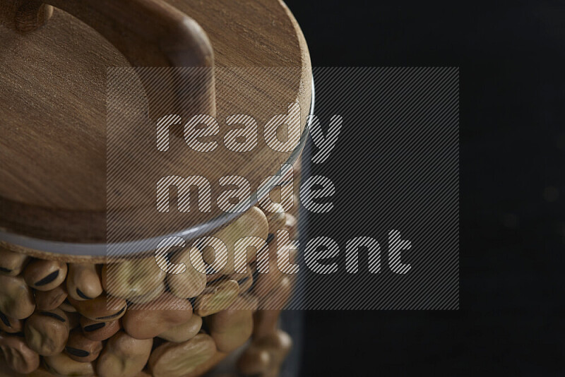 Fava beans in a glass jar on black background