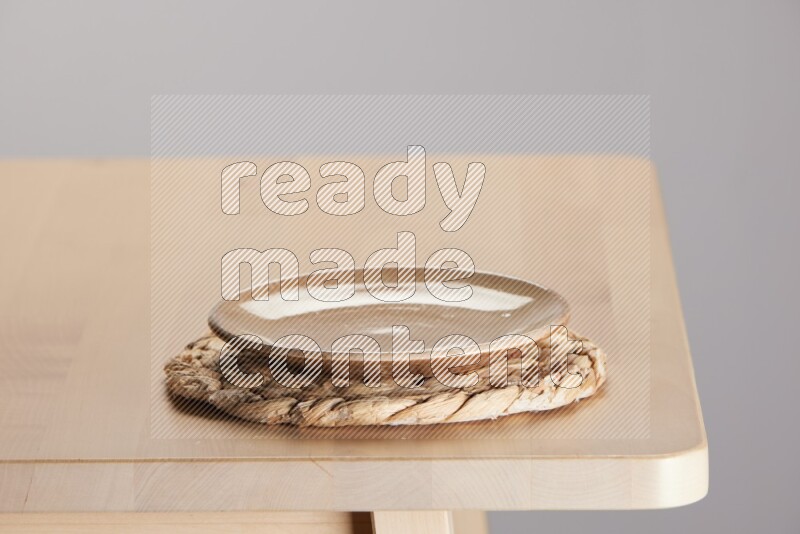 multi-colored pottery Plate placed on a small light colored straw placemat on the edge of wooden table