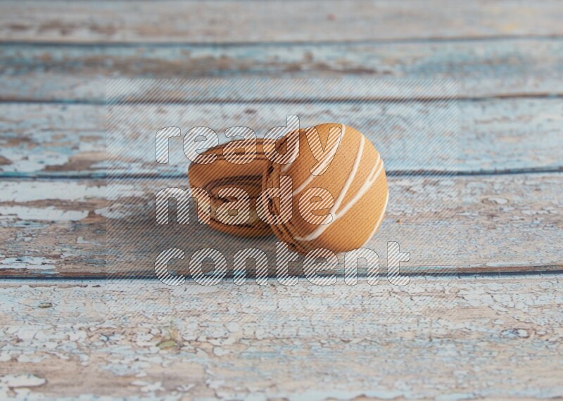 45º Shot of of two assorted Brown Irish Cream, and light brown Almond Cream macarons next to each other on light blue background