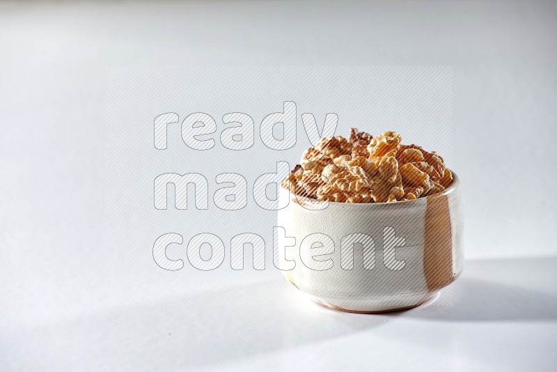 A beige ceramic bowl full of peeled walnuts on a white background in different angles