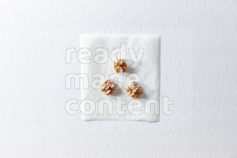 3 peeled walnuts on a piece of paper on a white background in different angles