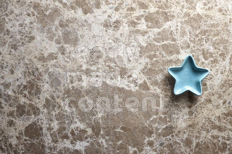 A pottery star plate on beige marble background