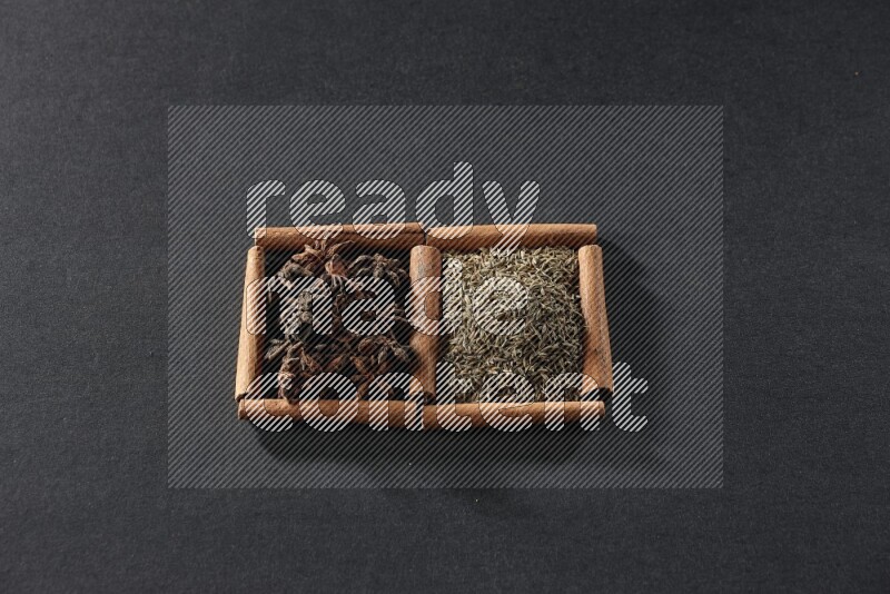 2 squares of cinnamon sticks full of cumin and star anise on black flooring