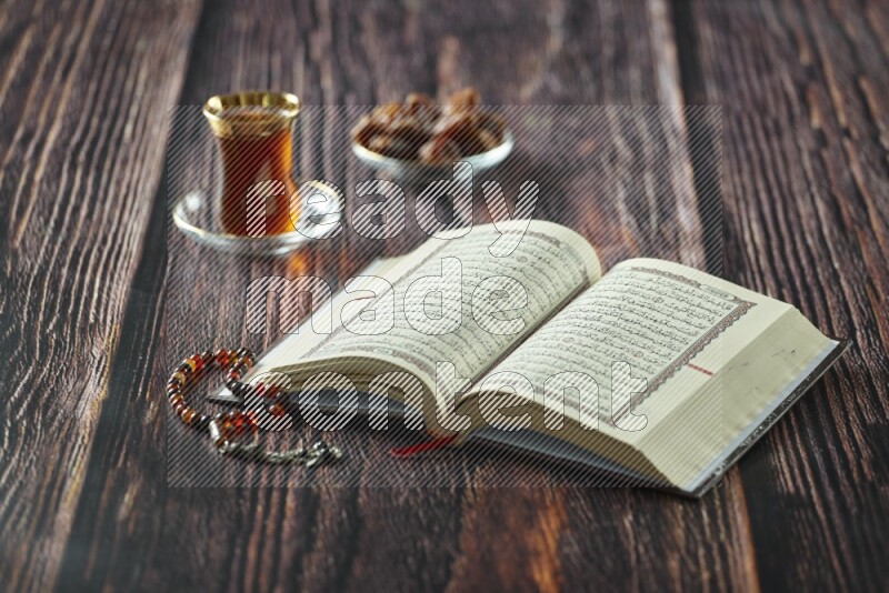 Quran with dates, prayer beads and different drinks all placed on wooden background