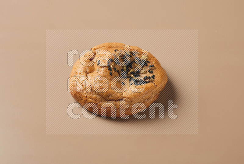 a whole Hasawi cookie with grains on a brown background