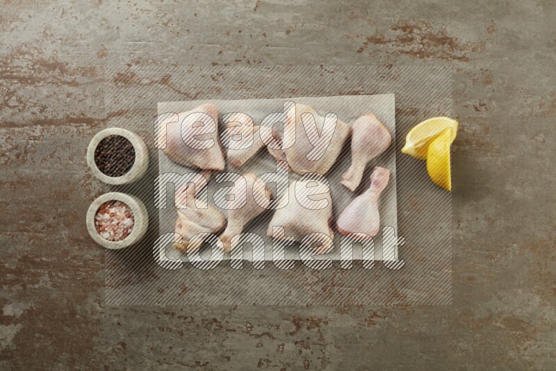 Mixed fresh chicken pieces on a parchment paper direct on a textured rustic background