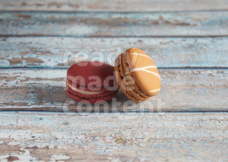 45º Shot of of two assorted Brown Irish Cream, and Red Velvet macarons on light blue background