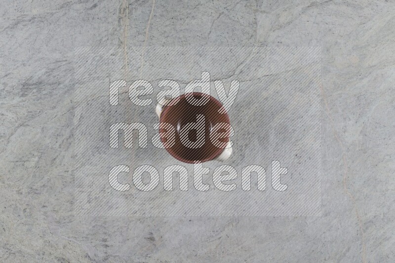 إناء فخاري متعدد الألوان مع غطائه على خلفية من الرخام الرمادي