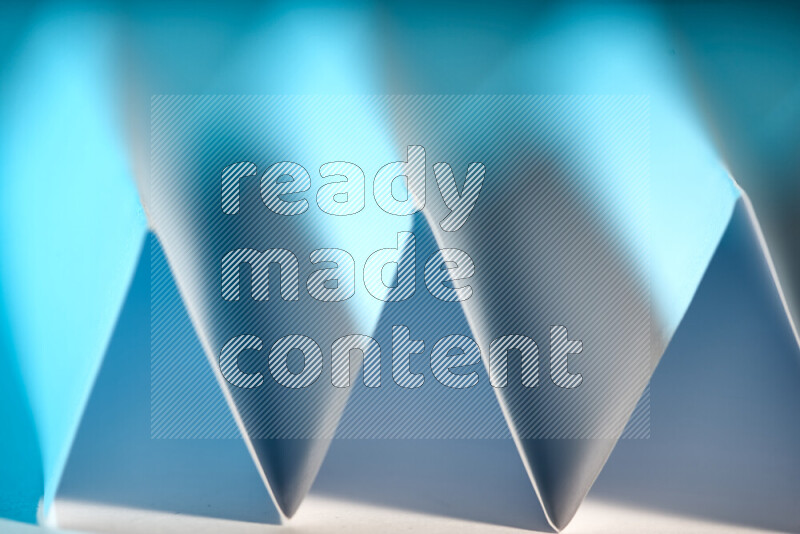 A close-up abstract image showing sharp geometric paper folds in blue gradients