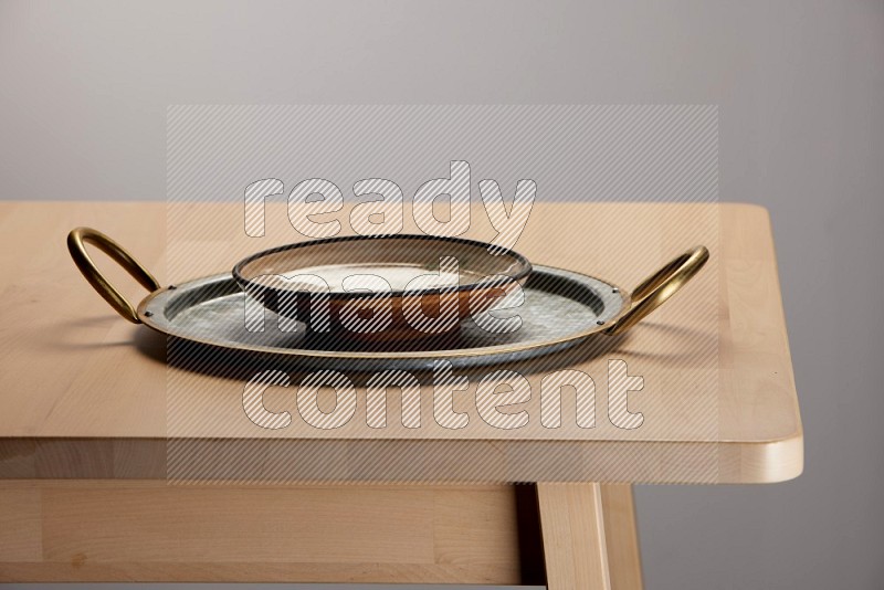 multicolored plate placed on a rounded stainless steel tray with golden handels on the edge of wooden table