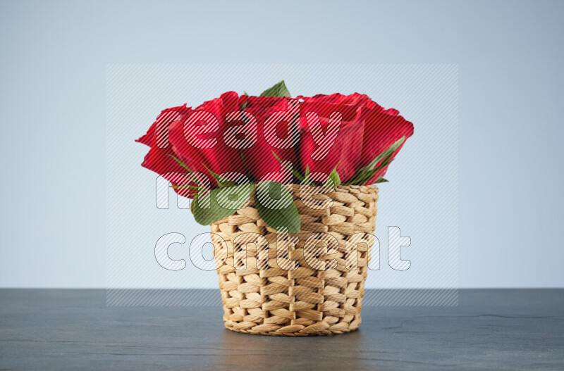 Vibrant red roses in a wicker basket on black marble background