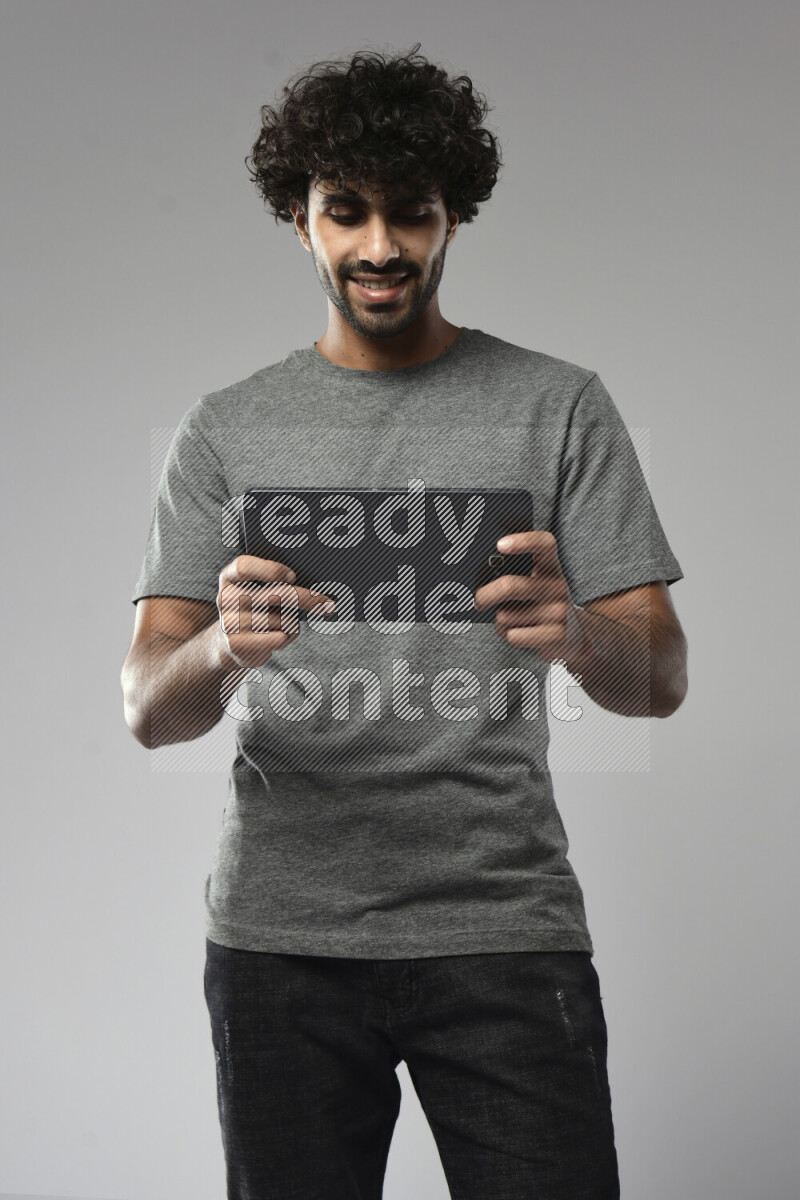 A man wearing casual standing and gaming on a tablet on white background