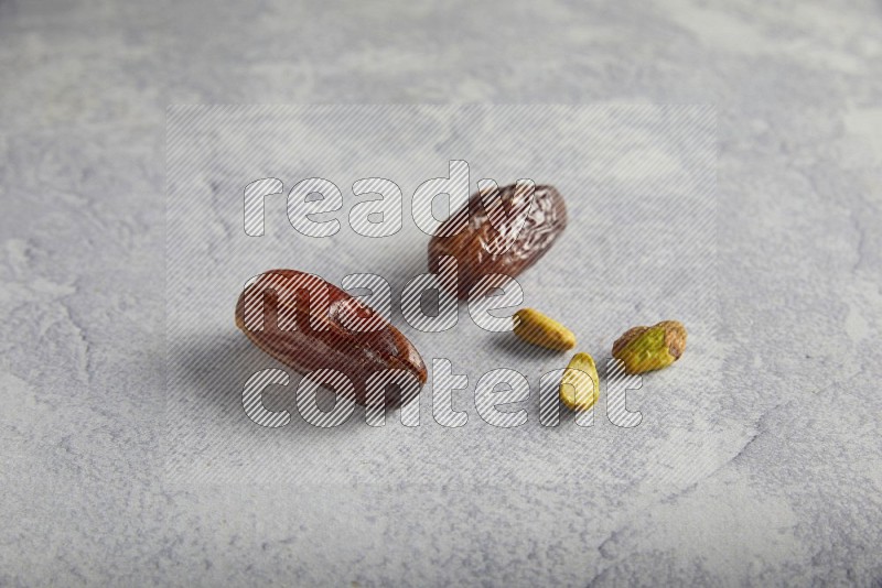 dates and unroasted pistachios on a light grey background