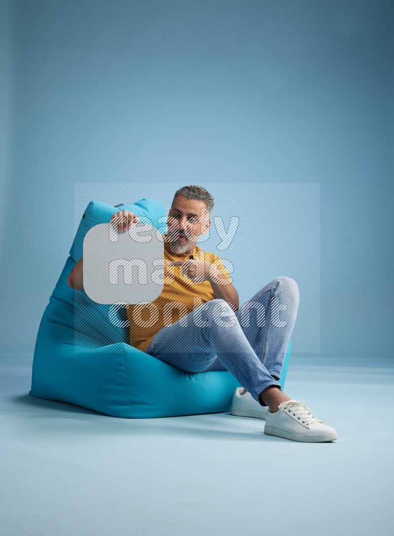 A man sitting on a blue beanbag and holding social media sign