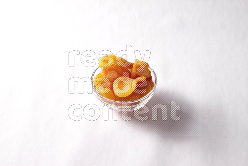 Dried apricots in a glass bowl on white background