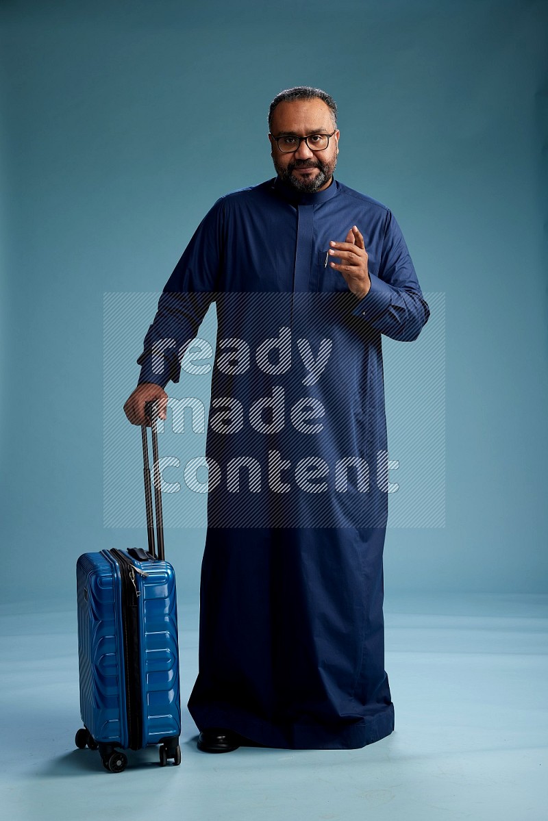 Saudi Man without shimag Standing pulling travel bag on blue background