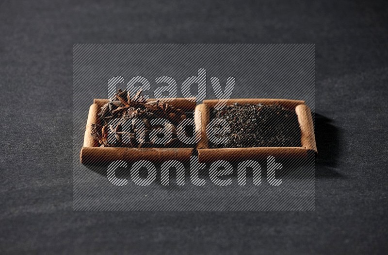 2 squares of cinnamon sticks full of star anise and black tea on black flooring