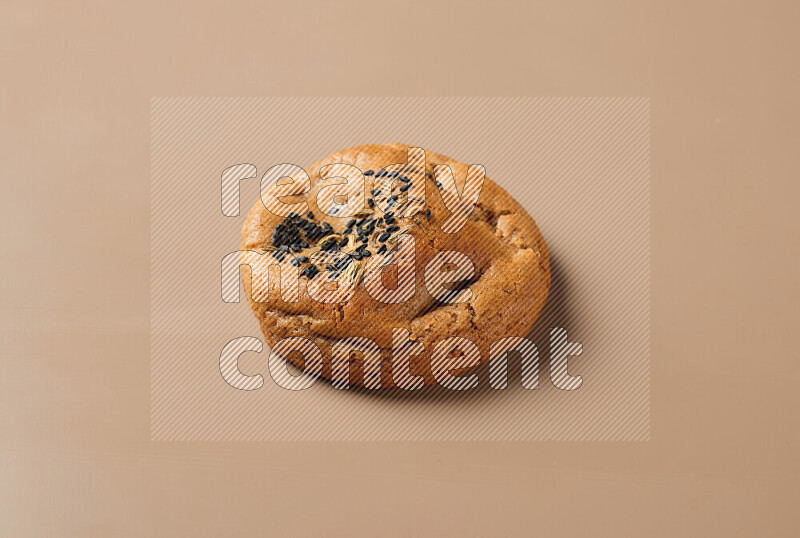 a whole Hasawi cookie with grains on a brown background