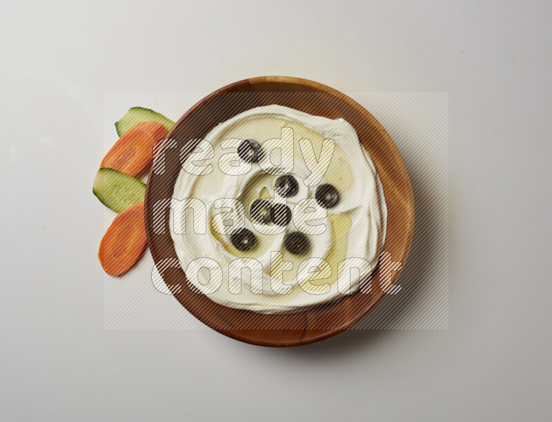 Lebnah garnished with sliced olives in a wooden plate on a white background