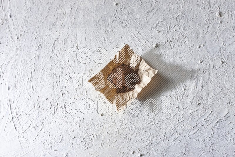 Cloves powder on crumpled piece of paper on a textured white flooring