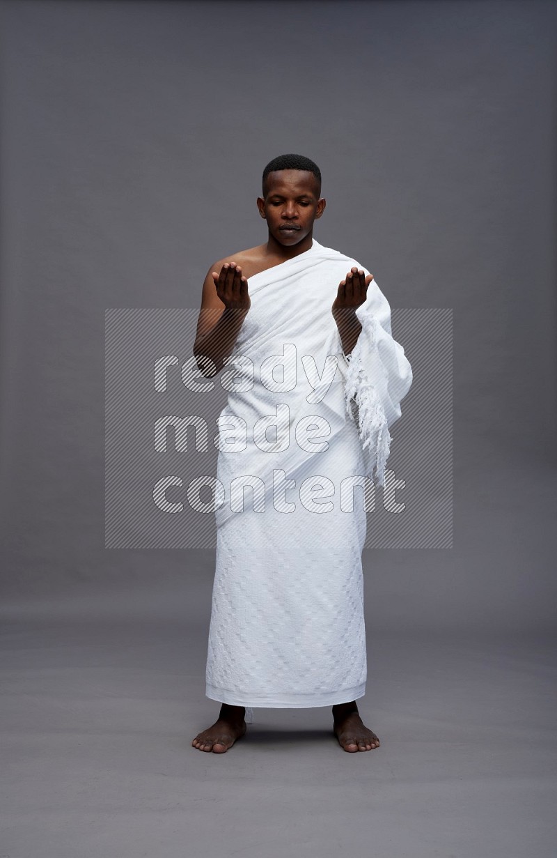 A man wearing Ehram Standing dua'a on gray background