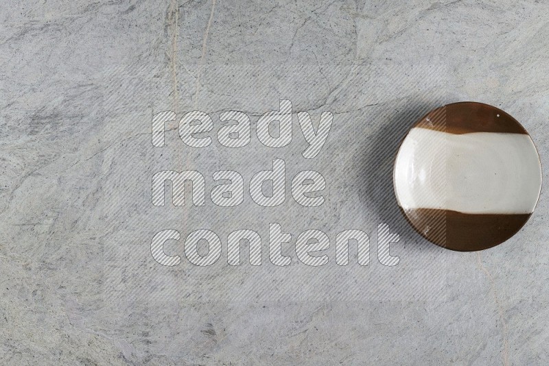 Top View Shot Of A Multicolored Pottery Plate On Grey Marble Flooring