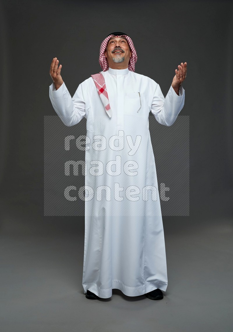 Saudi man with shomag Standing Interacting with the camera on gray background