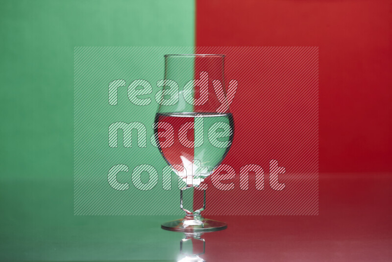 The image features a clear glassware filled with water, set against green and red background