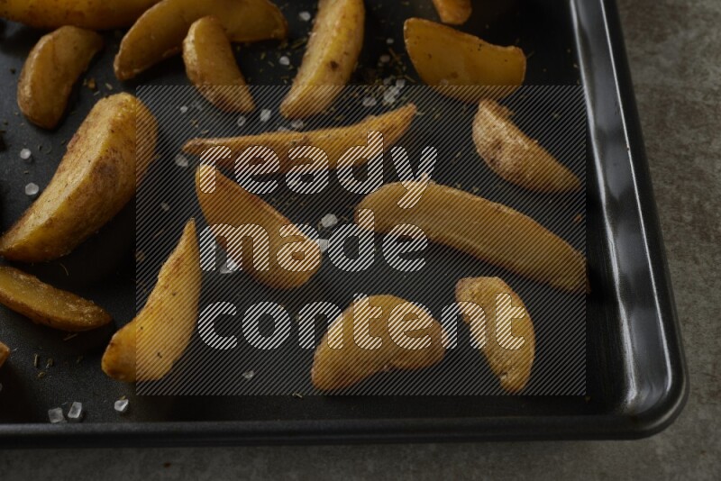 wedges potato in a black stainless steel rectangle tray on grey textured counter top