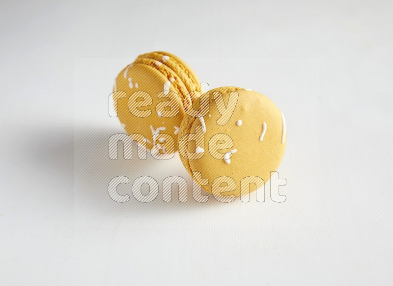 45º Shot of two Yellow Piña Colada macarons on white background