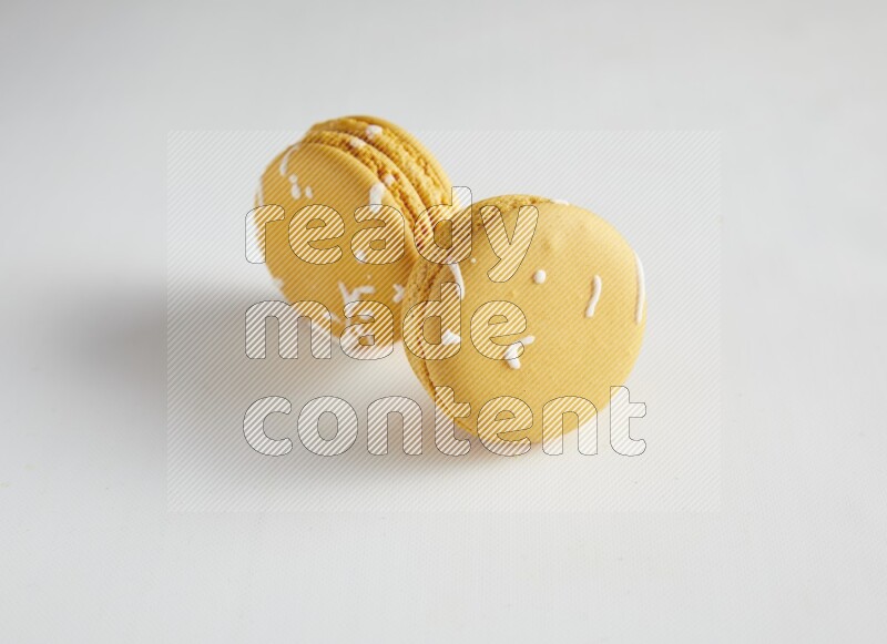 45º Shot of two Yellow Piña Colada macarons on white background